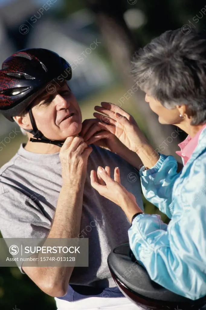 Woman helping a man put on a cycling helmet