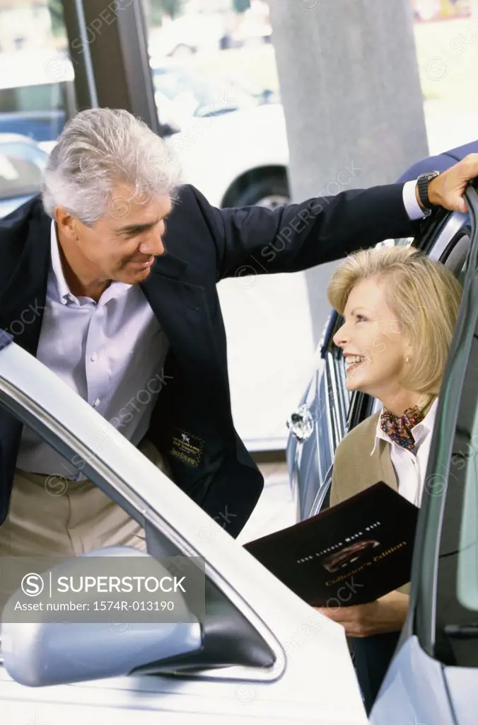 Mature man talking to a mature woman sitting in a car