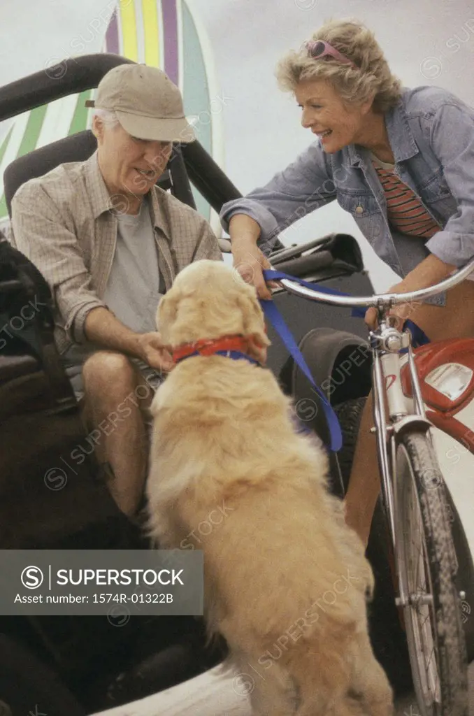 Senior couple on a jeep and bicycle with their dog