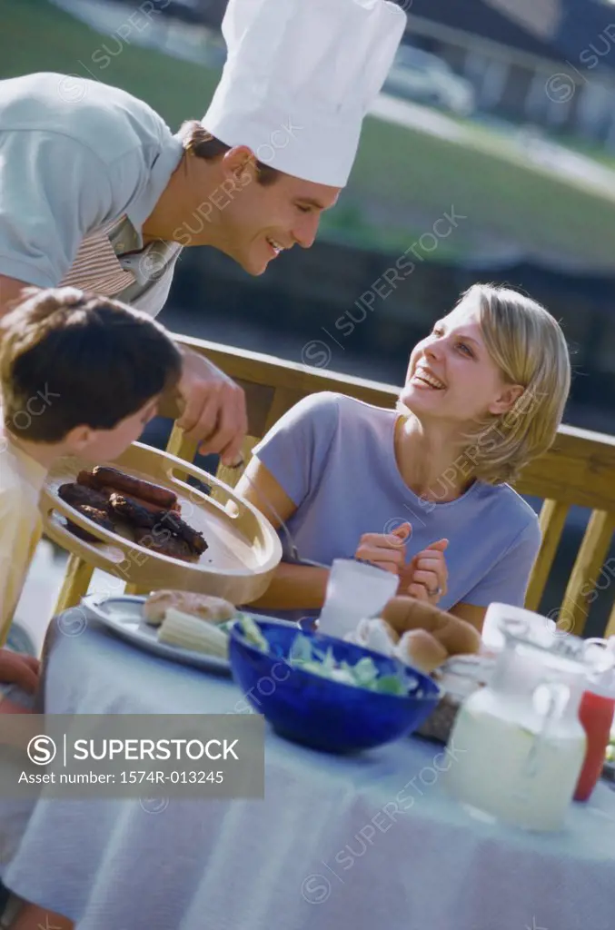 Mid adult man serving food to his son and wife