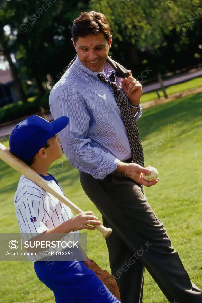 Side profile of a father walking in a park with his son carrying a baseball bat