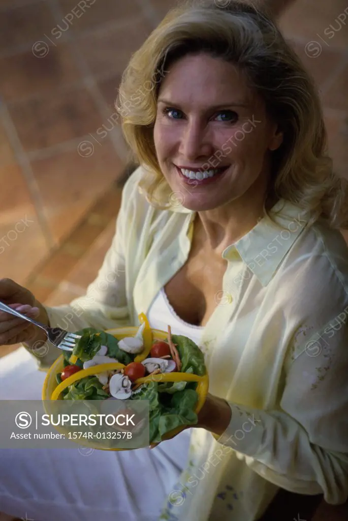 Portrait of a mature woman holding a plate of salad