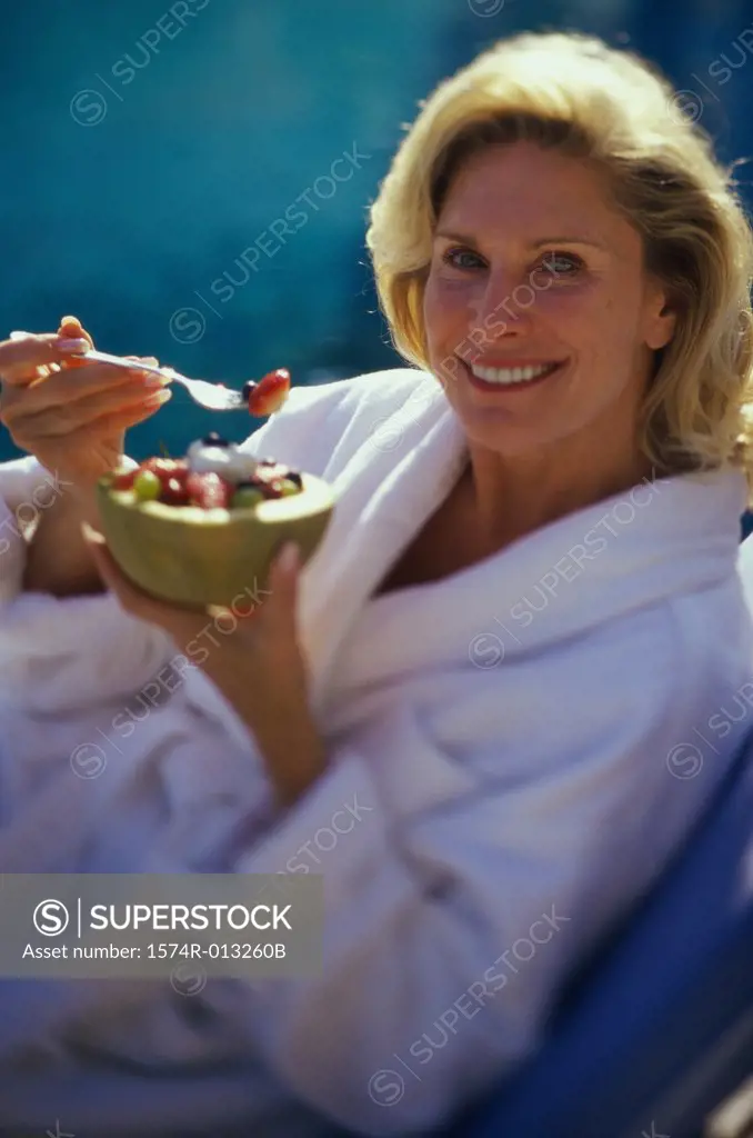 Portrait of a mature woman holding a bowl of fruit salad