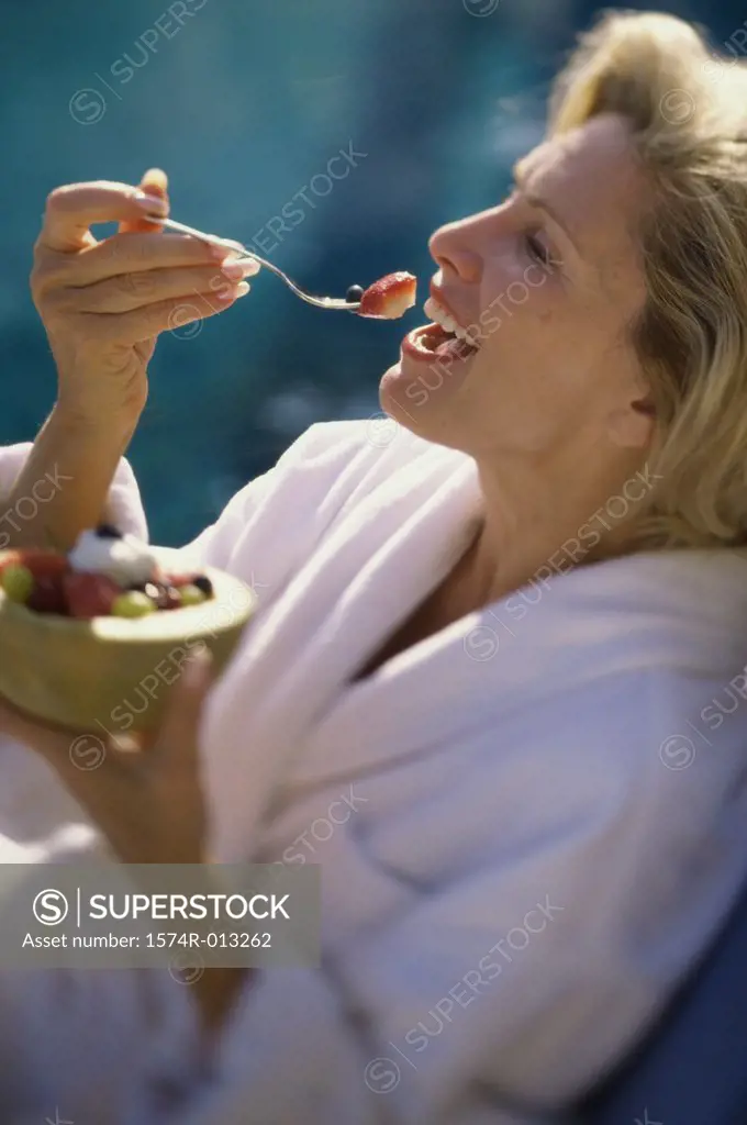 Close-up of a mature woman eating fruit salad