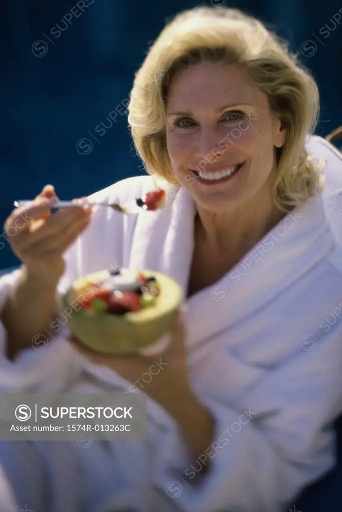 Portrait of a mature woman holding a bowl of fruit salad