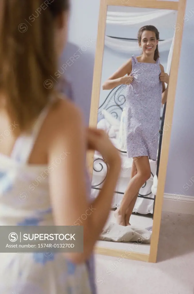 Teenage girl trying on a new dress in front of a mirror
