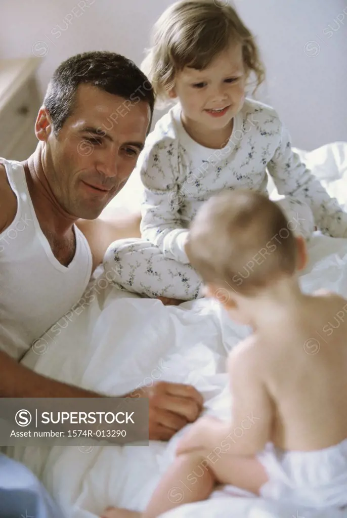 Father sitting with his son and daughter on a bed