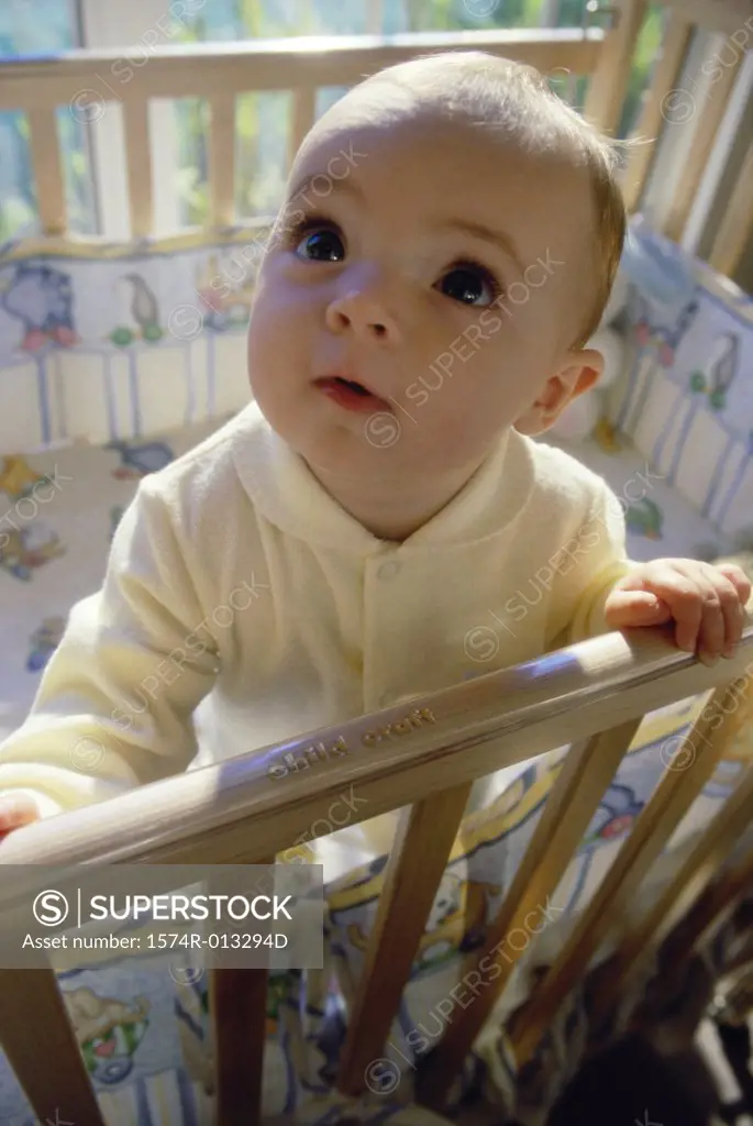 Close-up of a baby boy standing in a crib