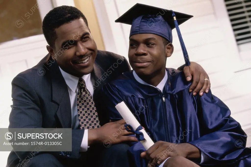 Close-up of a young male graduate sitting with his father