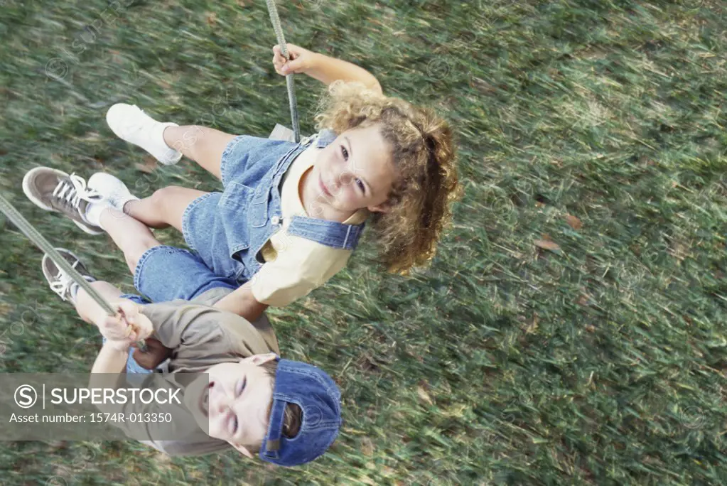 High angle view of a boy and girl swinging on a swing