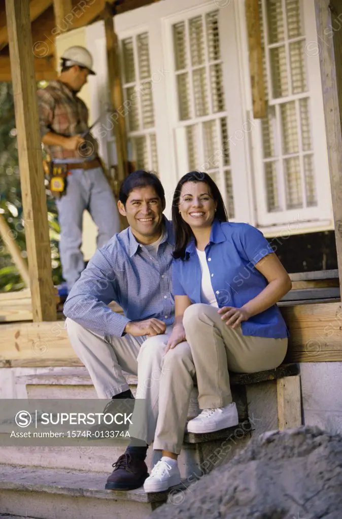 Portrait of a mid adult couple sitting on steps in front of their new house