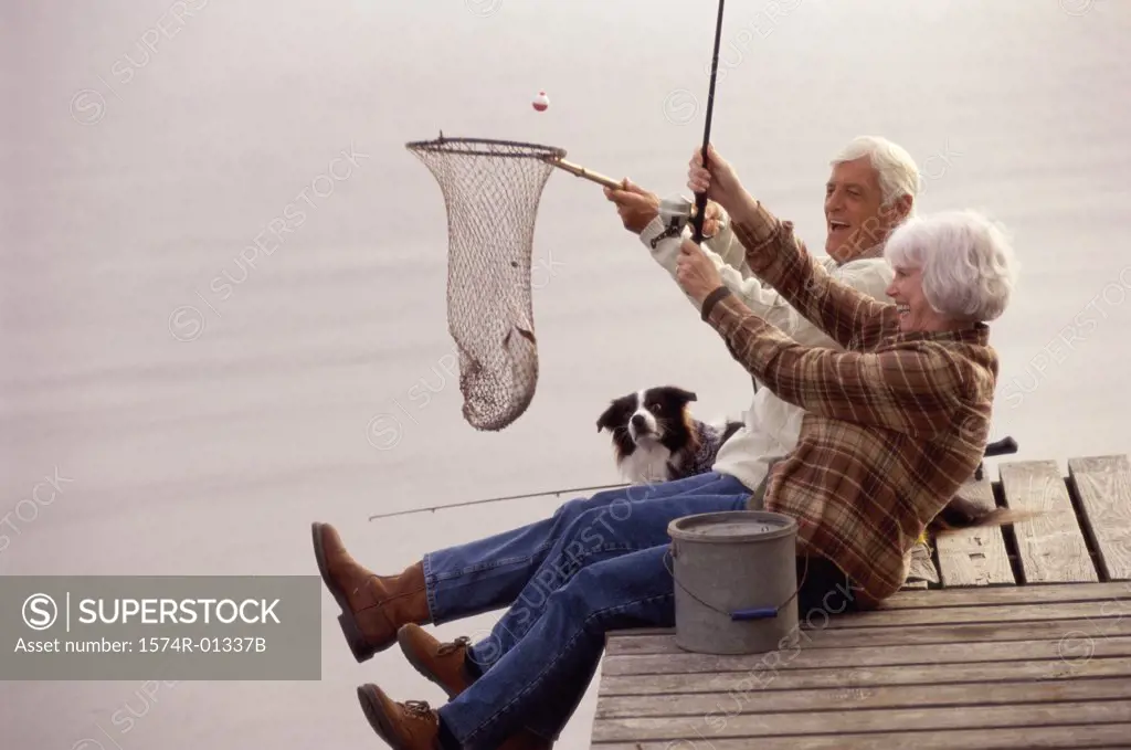 Side profile of a senior couple sitting on a pier fishing