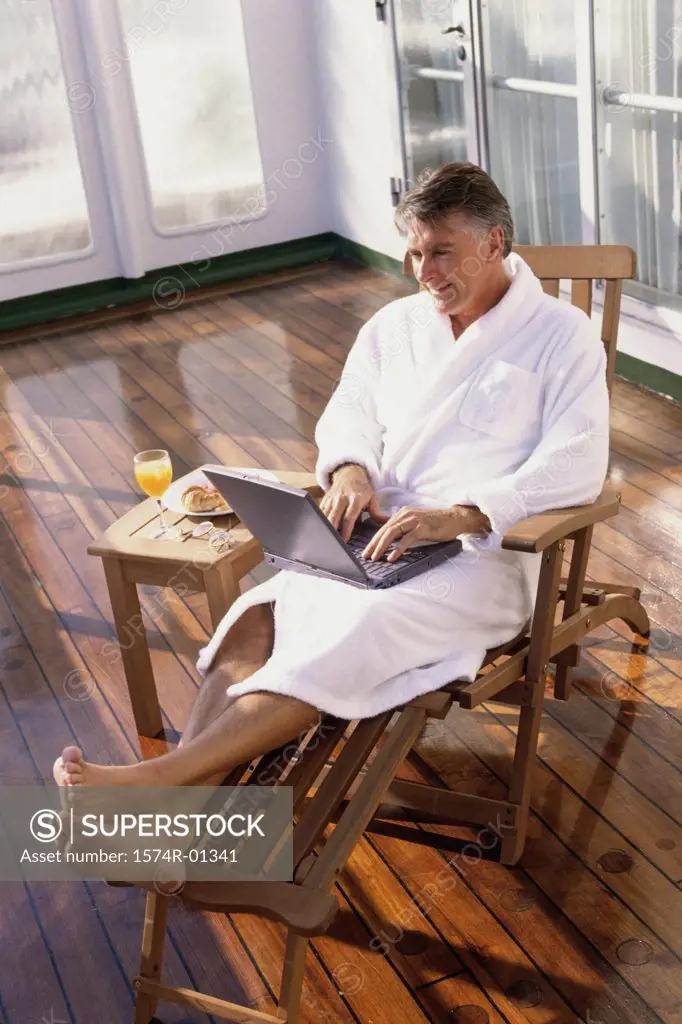 High angle view of a man in a bathrobe working on a laptop