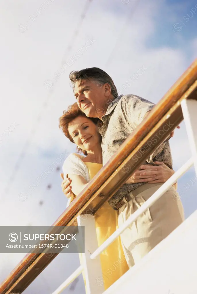 Low angle view of a couple standing against the railing of a ship