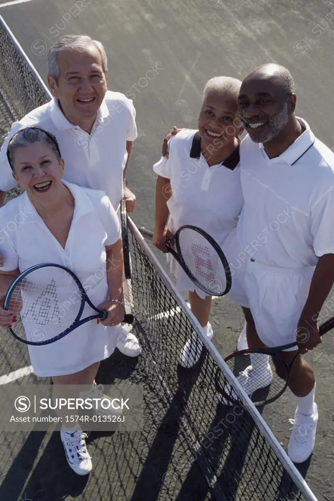High angle view of two senior couples standing on a tennis court