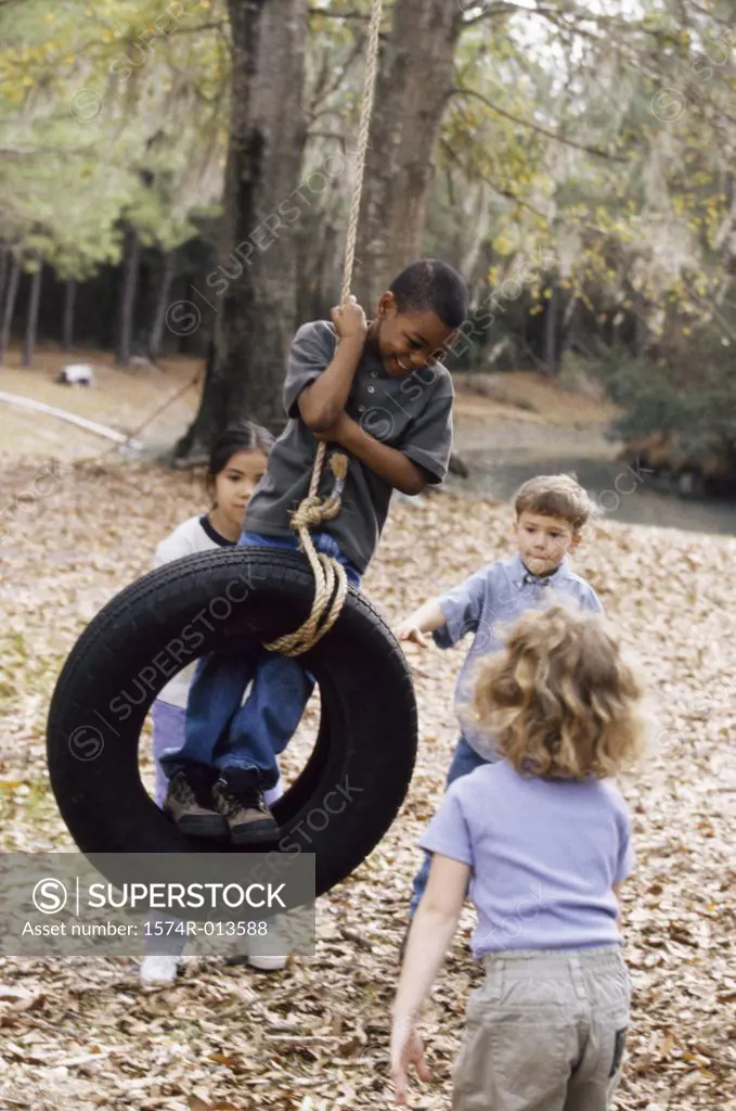 Two boys and two girls playing on a tire swing