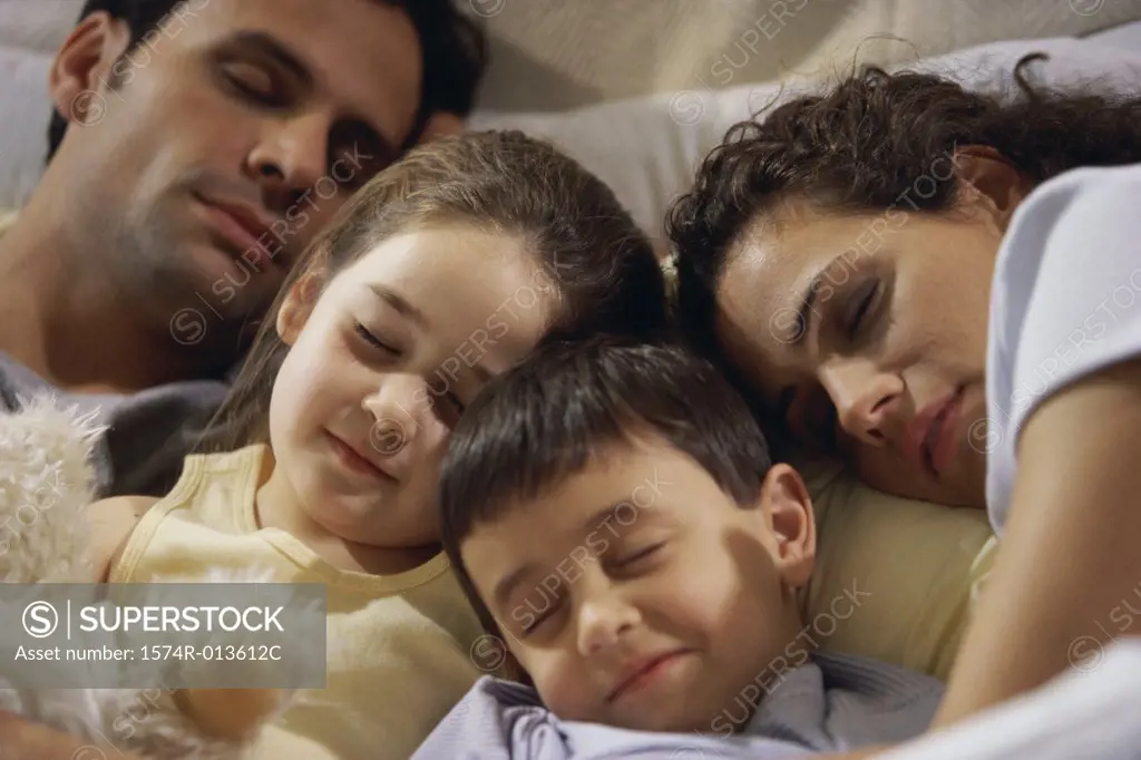 Close-up of parents with their two children sleeping on the bed