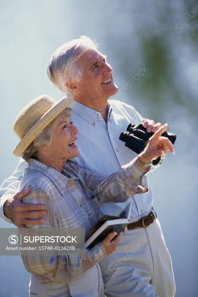 Senior couple standing together holding binoculars