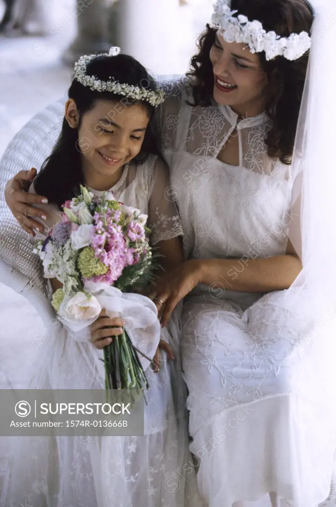 Close-up of a bride sitting with a flower girl