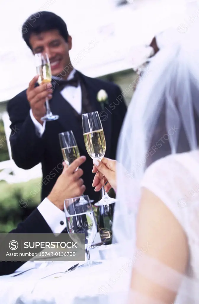 Newlywed couple and a wedding guest toasting with champagne