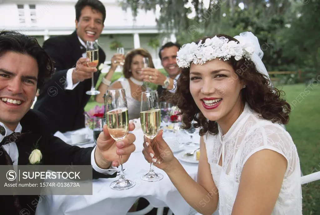Portrait of a newlywed couple sitting with their parents and wedding guests