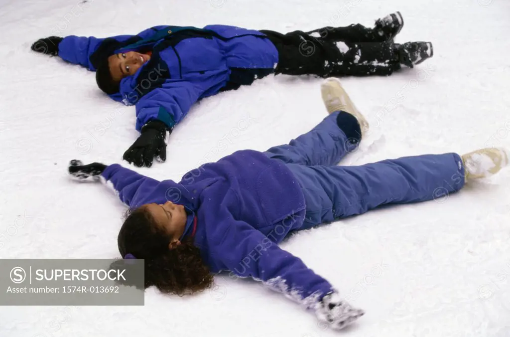 High angle view of two girls making snow angels