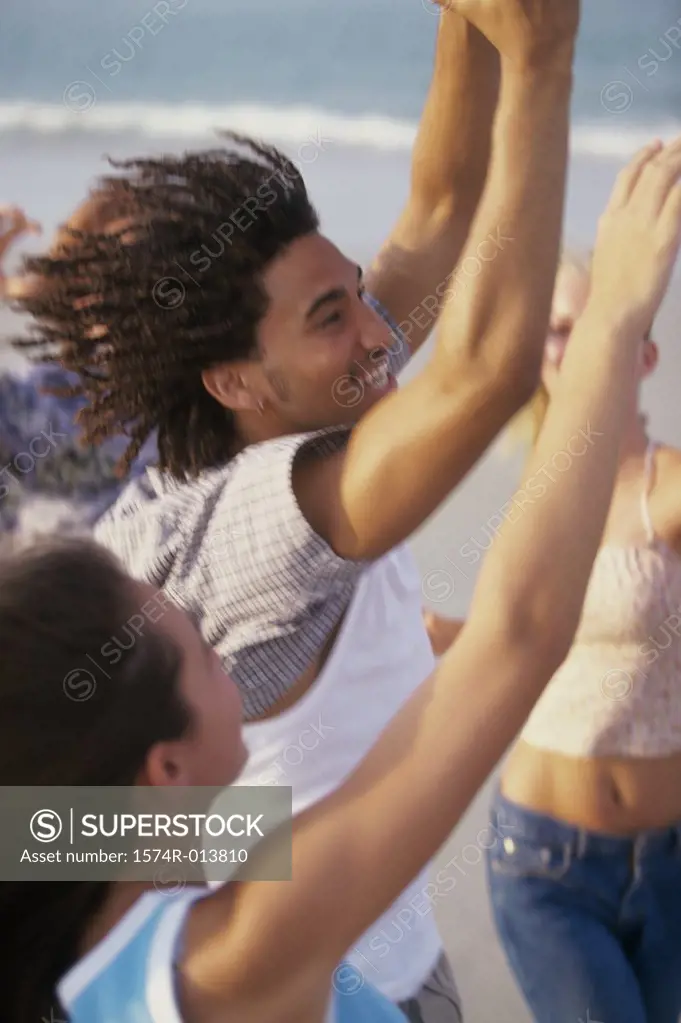 Side profile of a teenage boy and two teenage girls with their arms raised