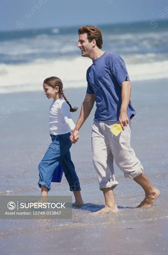 Side profile of a father and daughter walking on the beach