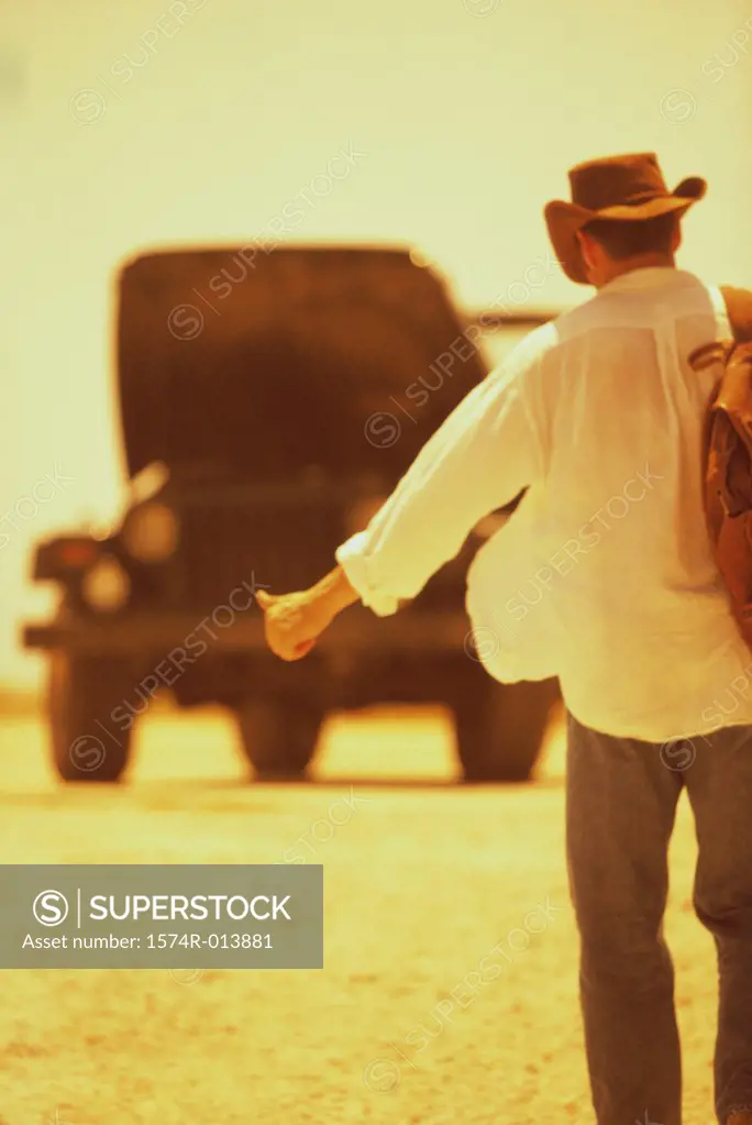 Rear view of a young man hitchhiking