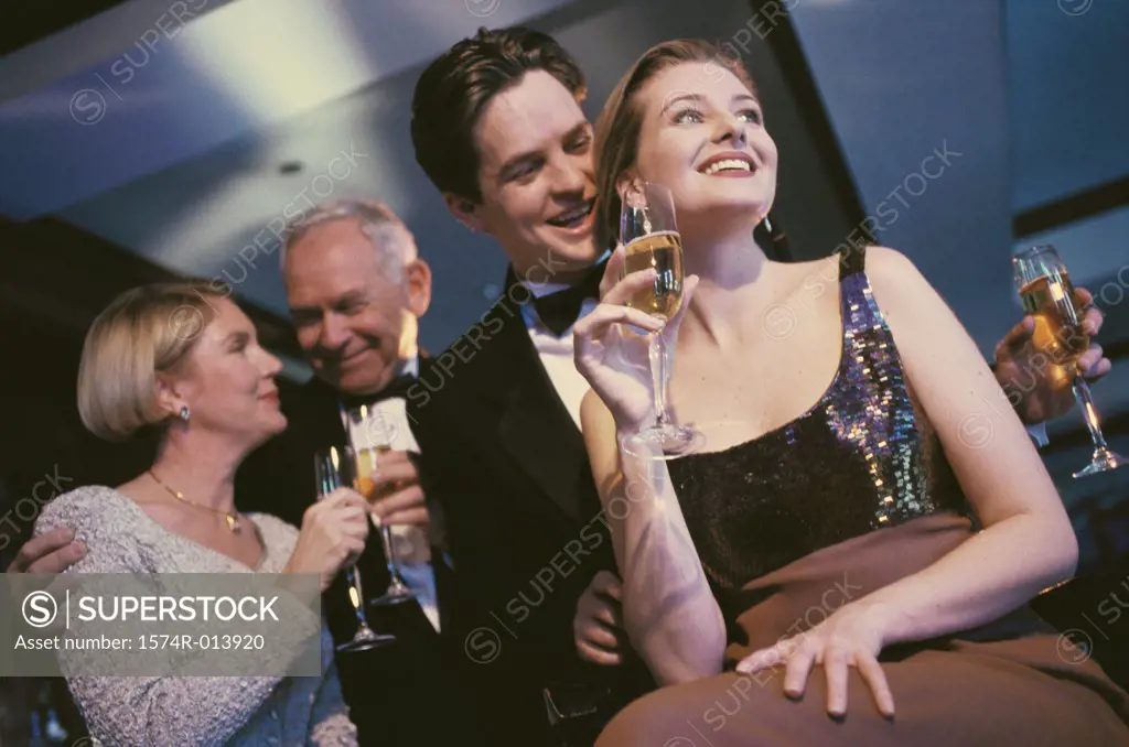 Low angle view of a young couple and senior couple holding glasses of champagne at a bar
