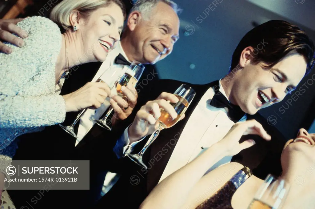 Close-up of a young couple and senior couple holding glasses of champagne at a bar