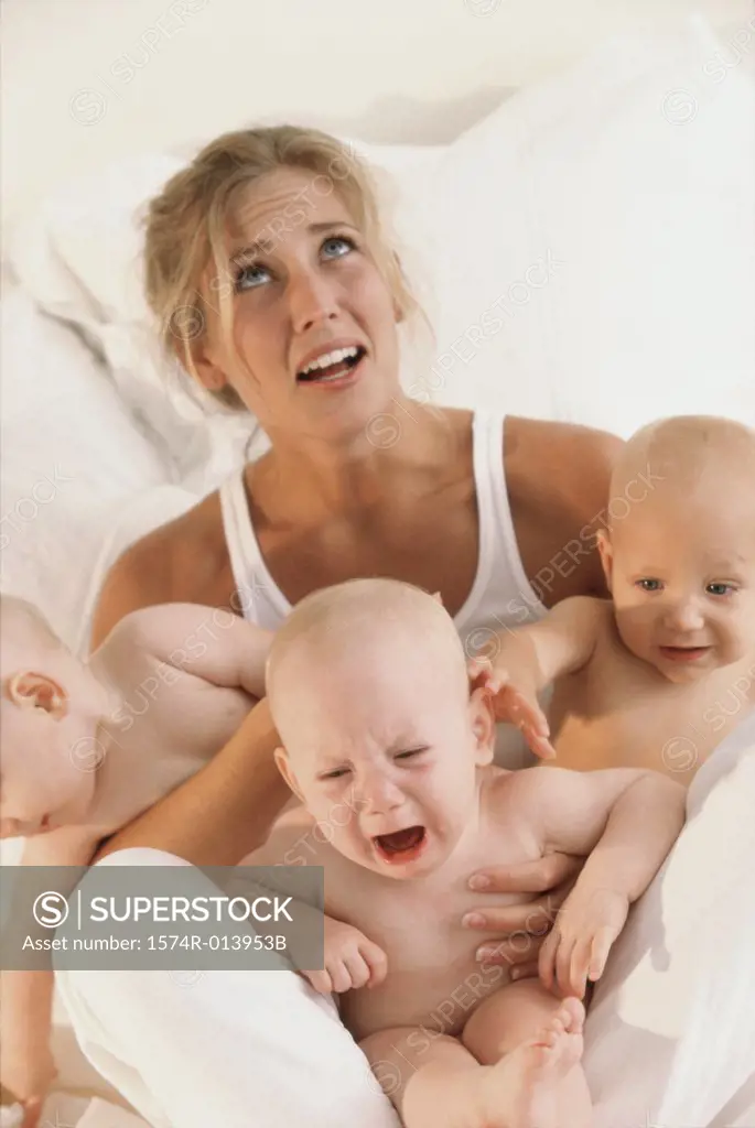 Portrait of a mother sitting on a bed with her three baby boys