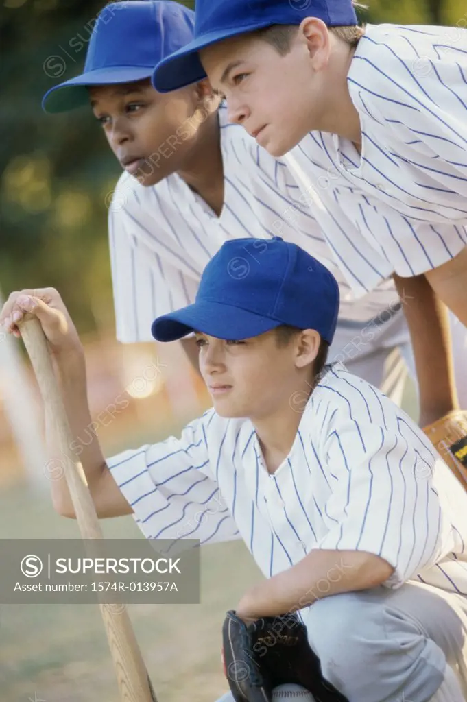 Close-up of three baseball players with a baseball bat