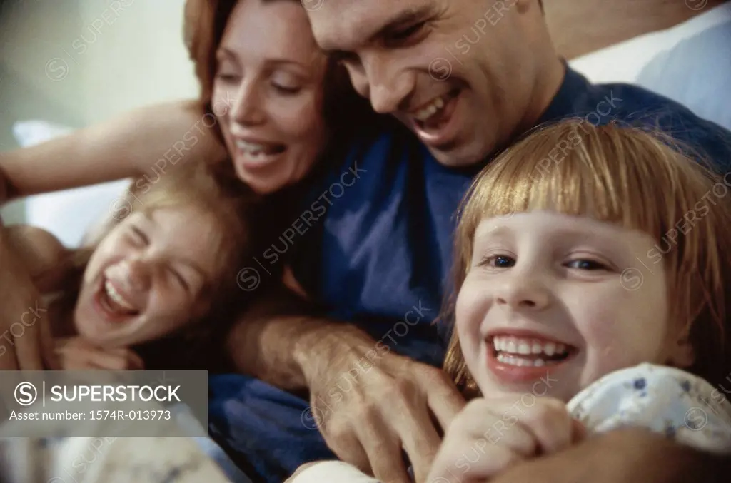 Close-up of parents and their two children playing in bed