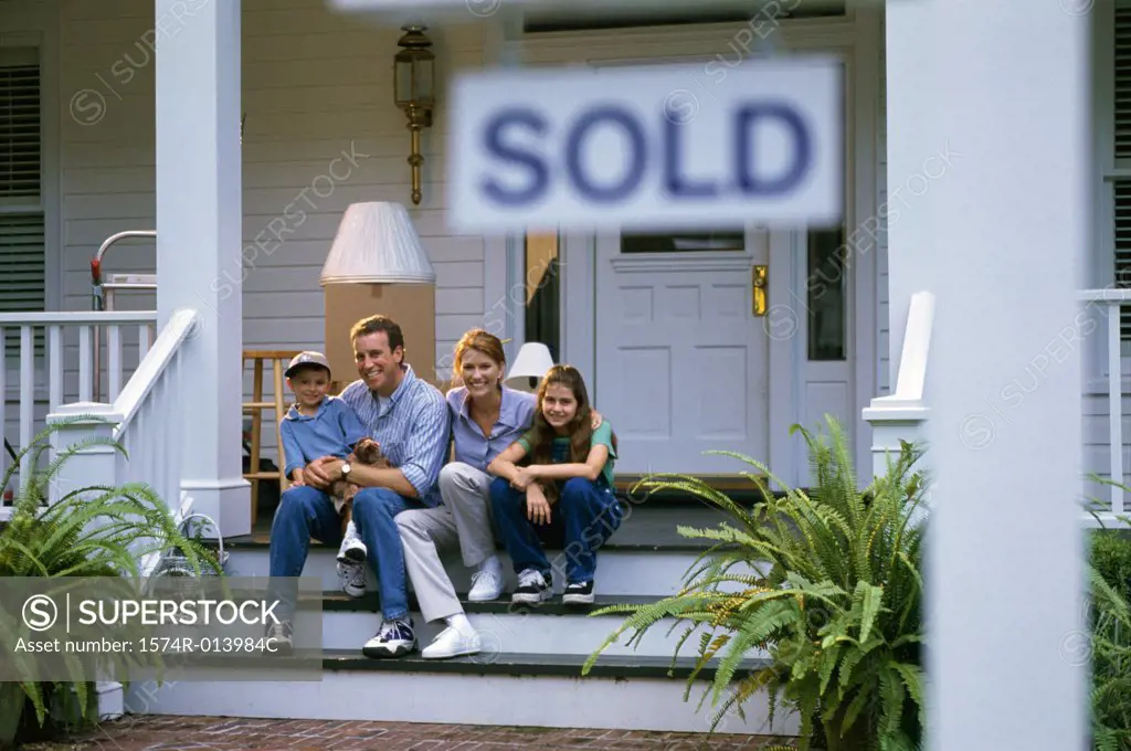 Portrait of parents sitting on the stairs of a house with their son and daughter