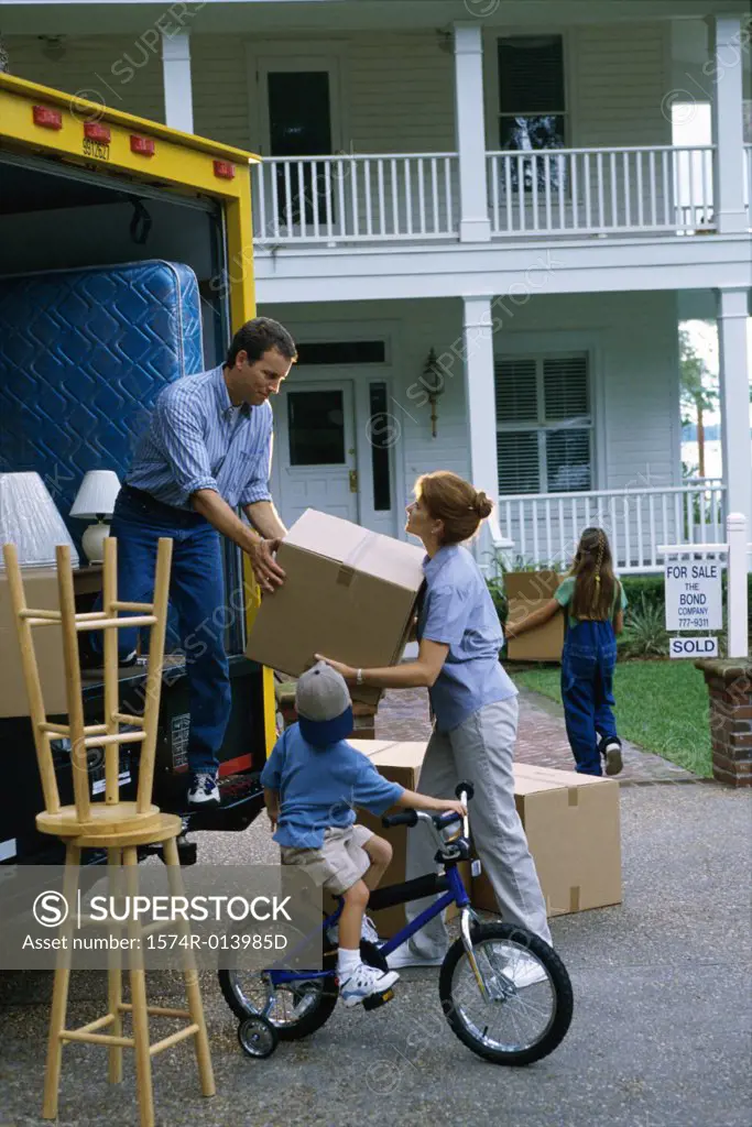 Mid adult couple unloading cardboard boxes from a moving van