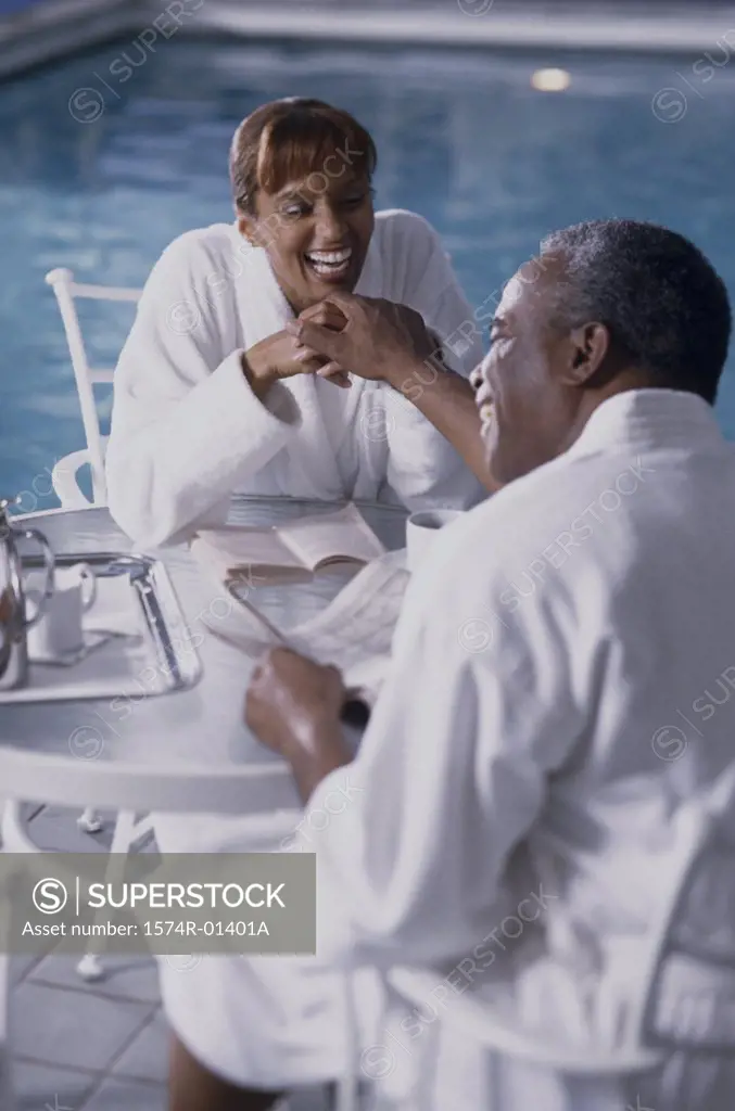 Couple sitting beside a swimming pool