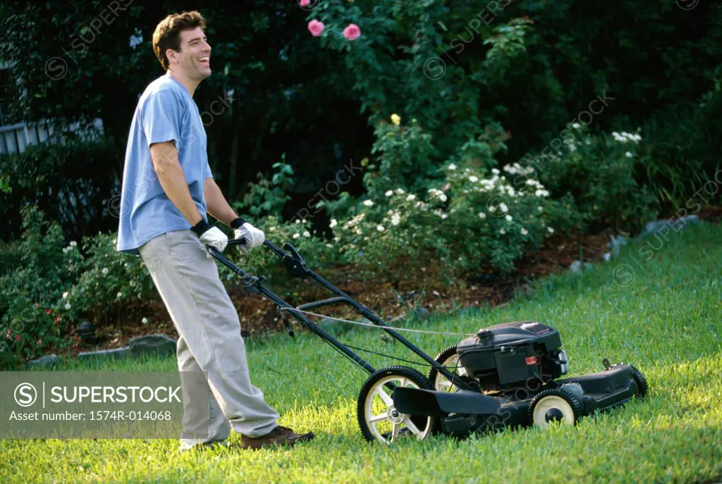 Side profile of a mid adult man mowing the lawn