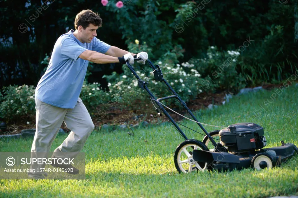 Mid adult man mowing the lawn with a lawn mower