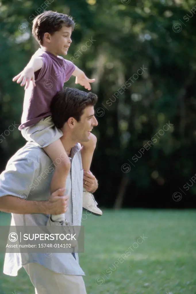 Side profile of a father carrying his son on his shoulders
