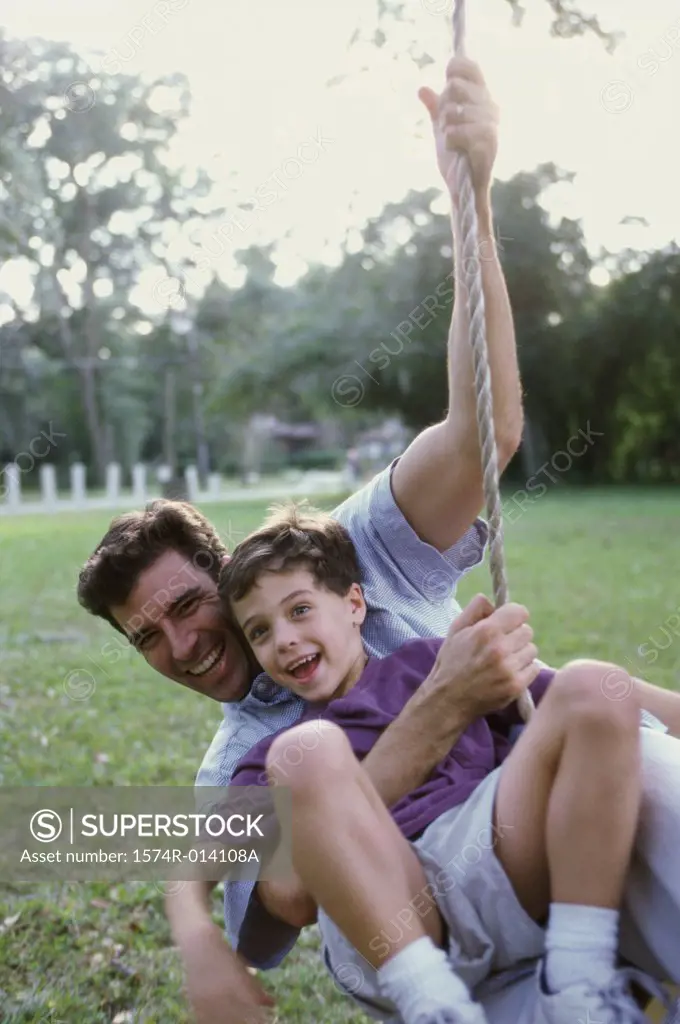 Father and son swinging on a rope swing