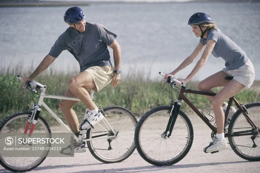 Side profile of a mature couple cycling on the road