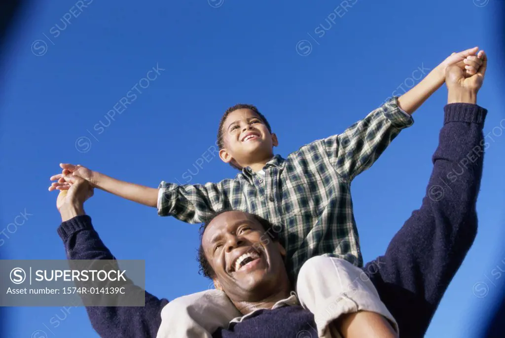 Low angle view of a father carrying his son on his shoulders