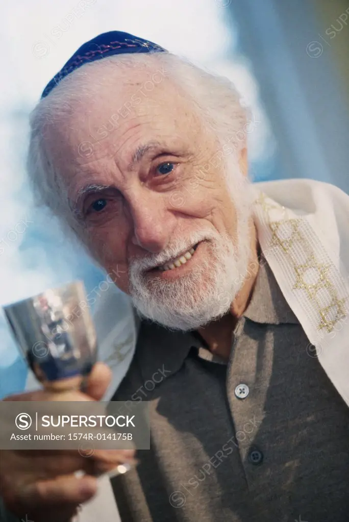 Portrait of a senior man holding a goblet at a Hanukkah ceremony