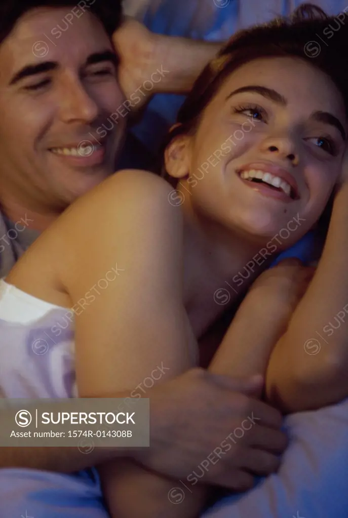 Close-up of a young couple embracing in bed