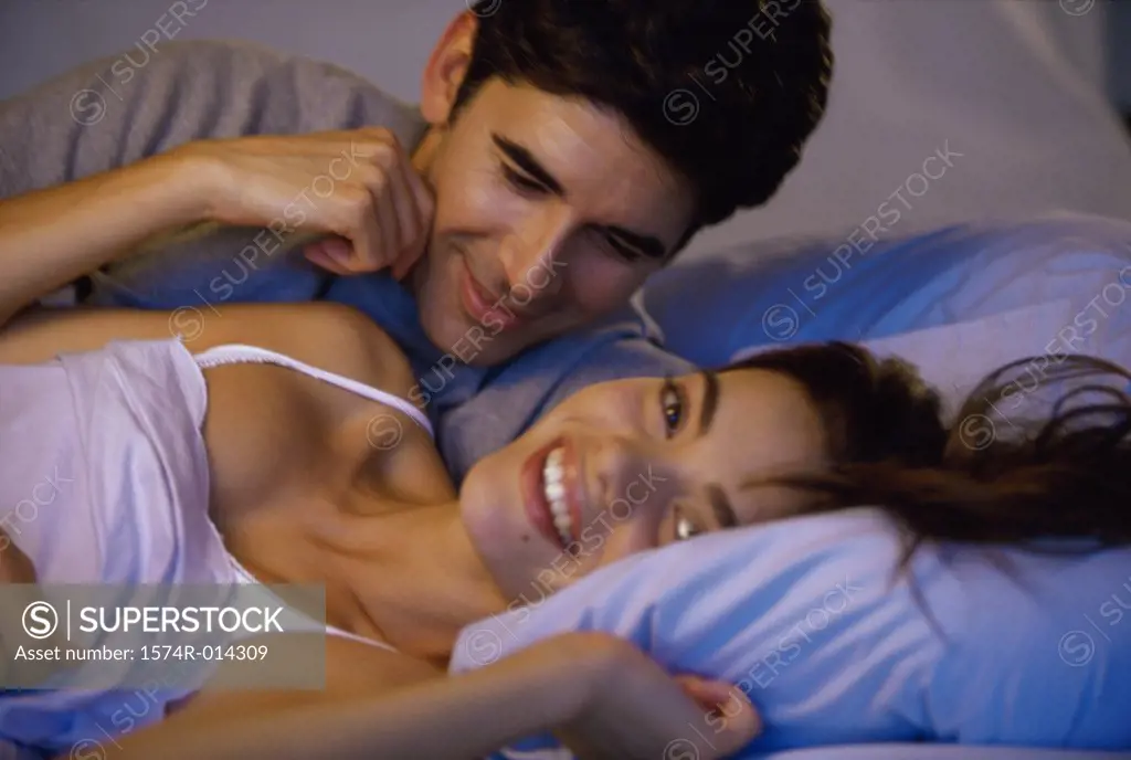Close-up of a young couple embracing in bed