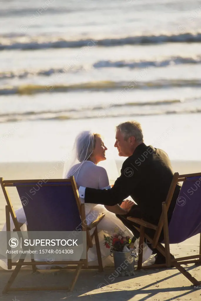 Senior couple sitting on deck chairs on the beach