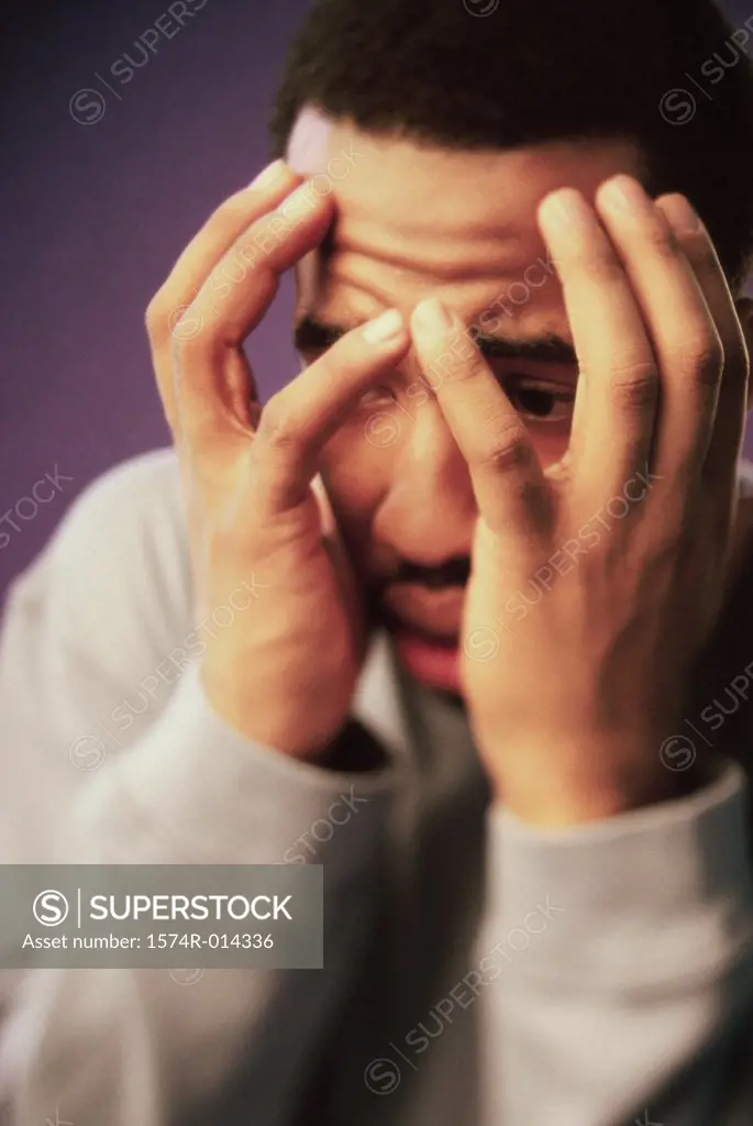 Close-up of a young man covering his face with his hands