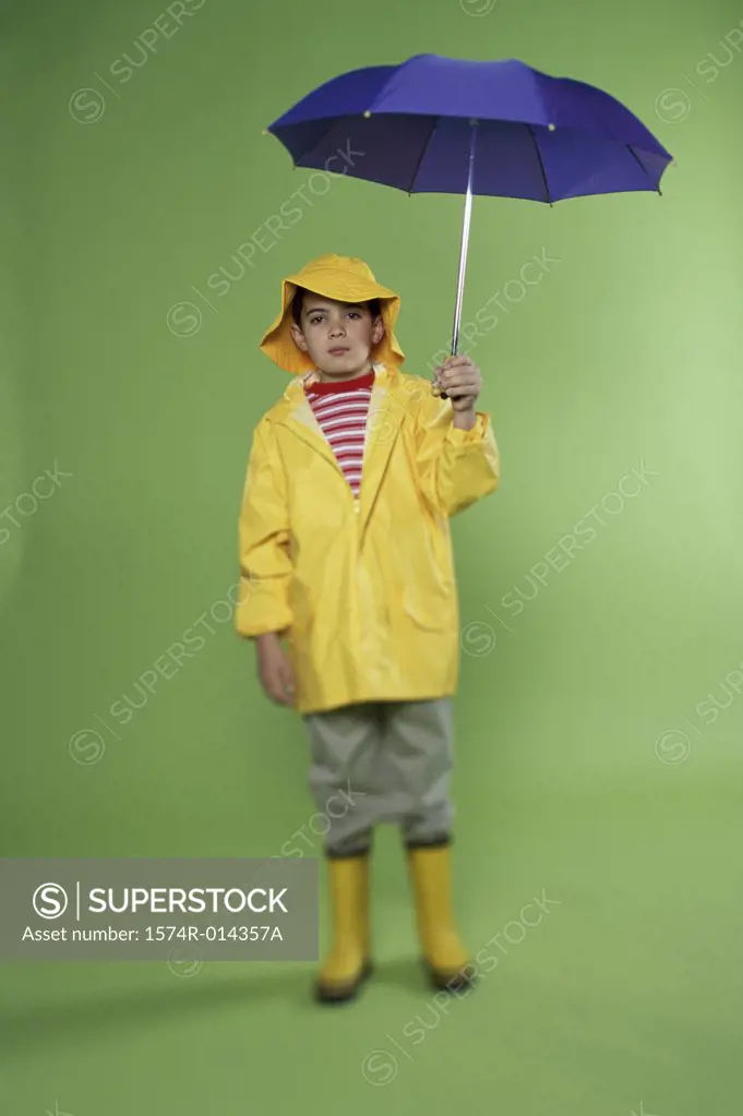 Portrait of a boy wearing a raincoat holding an umbrella