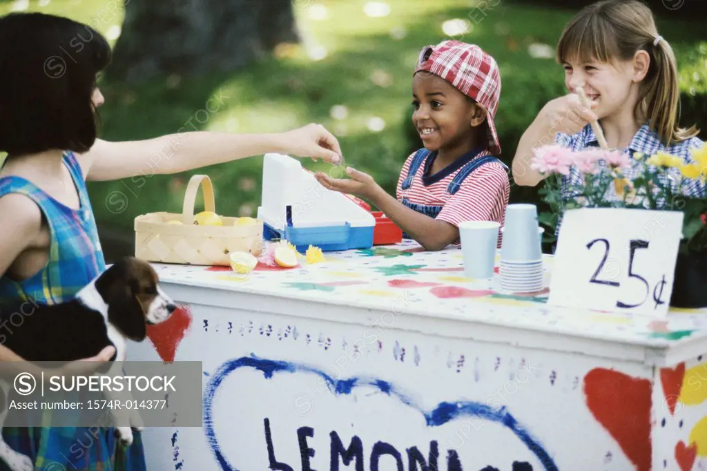 Two girls and a boy standing at a lemonade stand